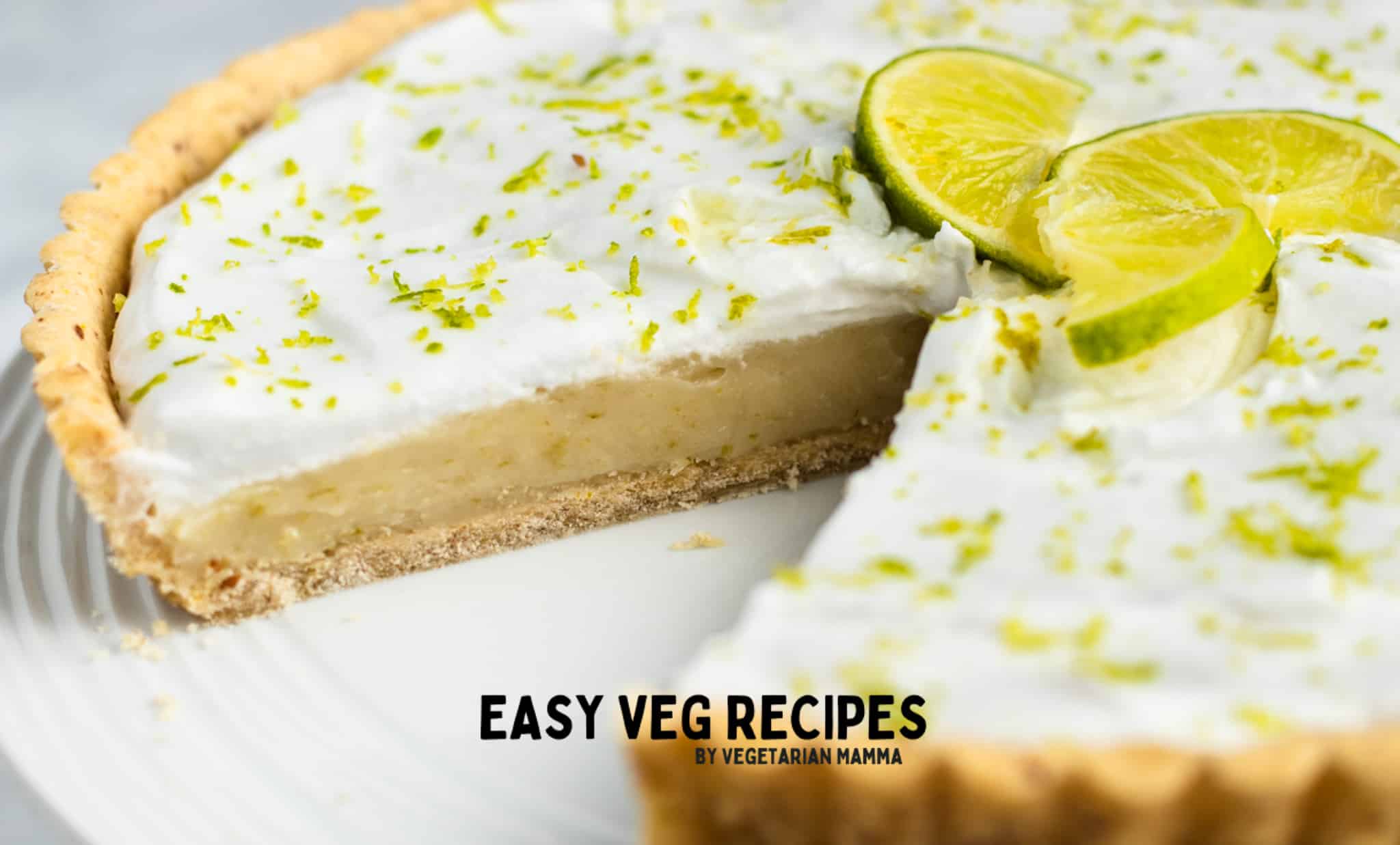 Vegan key lime pie on a plate, with one slice removed.
