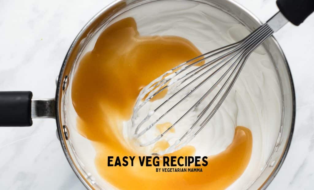 vegan condensed milk stirred into coconut whipped cream with a whisk.