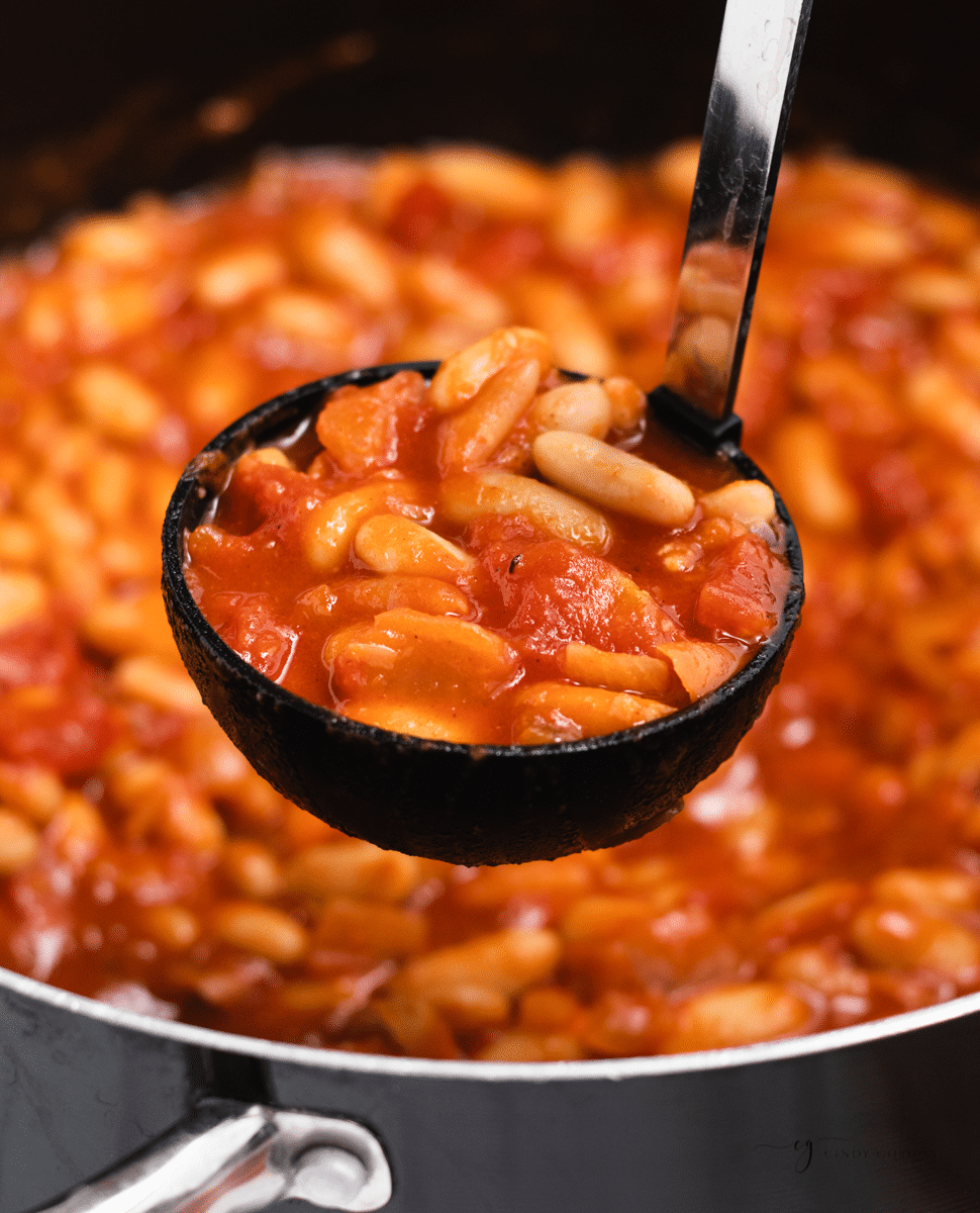baked beans ladeled out of a stockpot. 