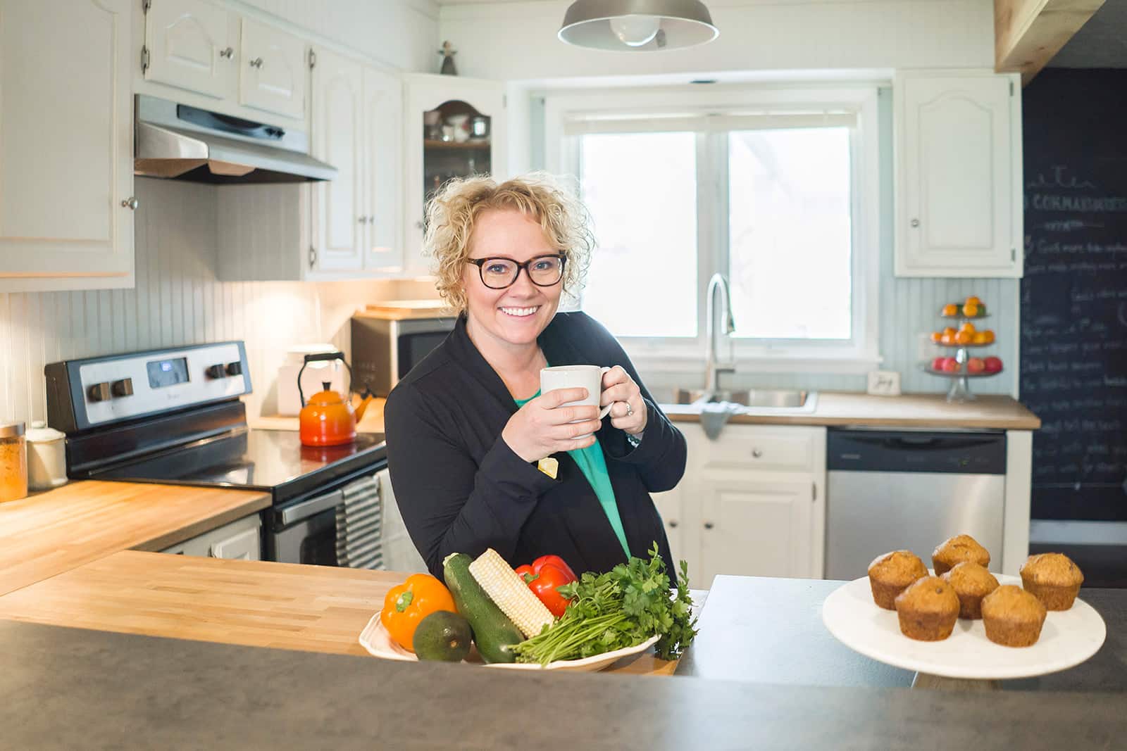 cindy in a white kitchen holding a white mug and smiling