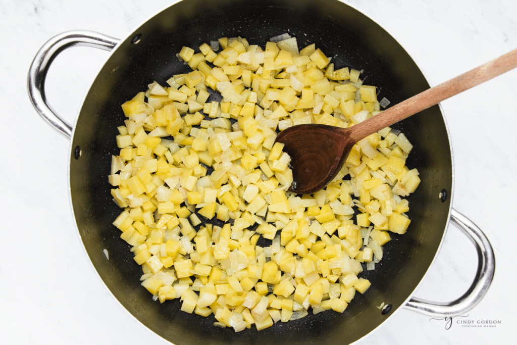 Potatoes and onions sauteeing in a pot.