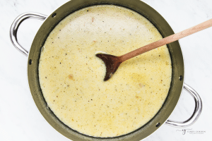 creamy four ingredient potato soup in a stock pot, stirred with a large wooden spoon.