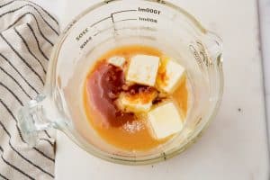 butter and vanilla added to caramel sauce in a measuring cup