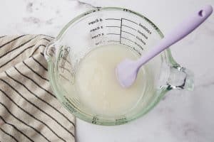 sugar and water in a measuring cup with a small purple spatula.