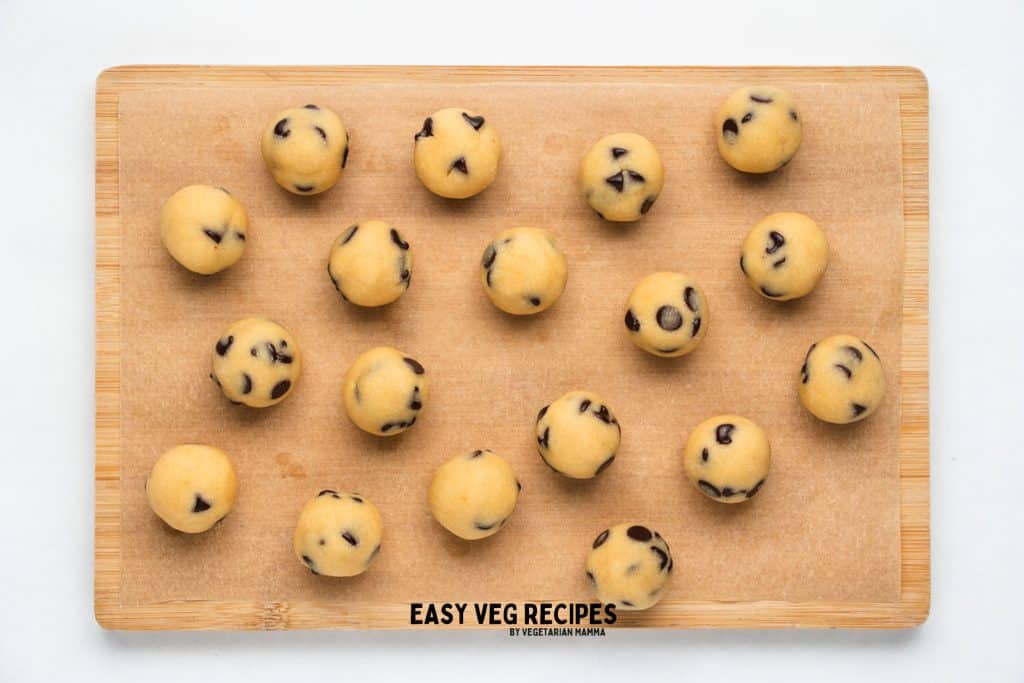 a wooden cuting board holding no bake cookie dough bites.