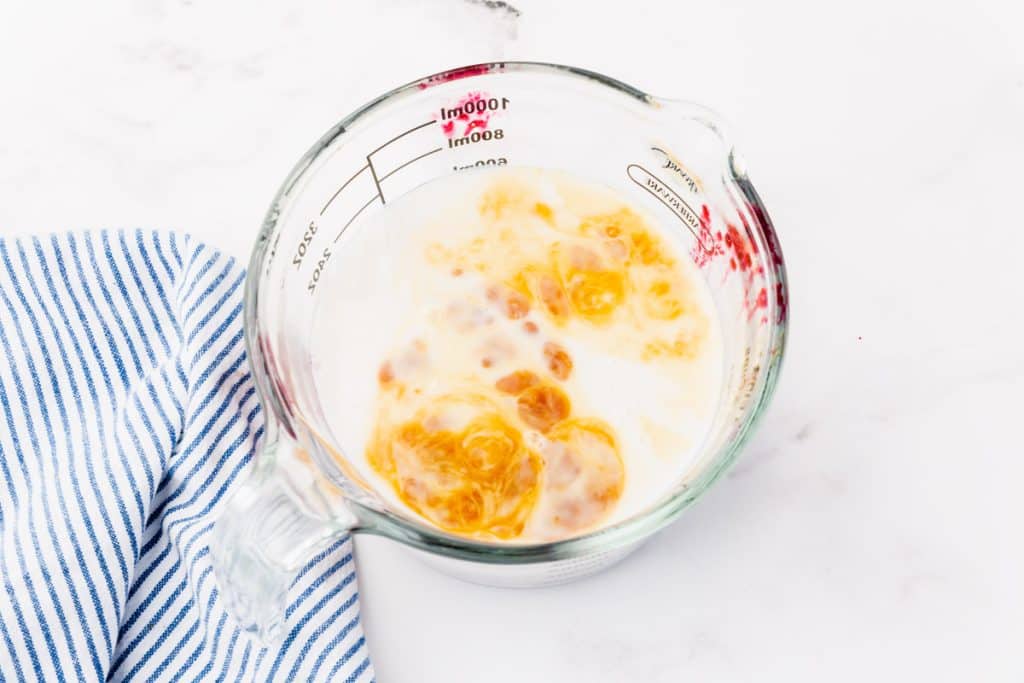a measuring cup with milk and vanilla.