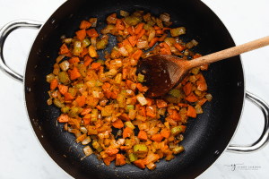 veggies cooked down in a pan with a wooden spoon for soup.