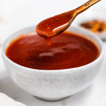 spicy red dragon sauce in a white bowl with a spoon.