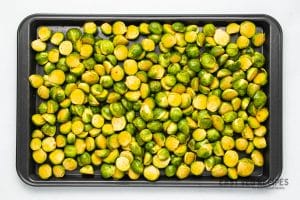 a sheet tray of raw, halved brussel sprouts.