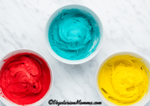 Add a few drops of red food coloring to one bowl, yellow to the second and blue to the third. Mix each bowlful well. Then chill the mixtures in the freezer for about 30 minutes.