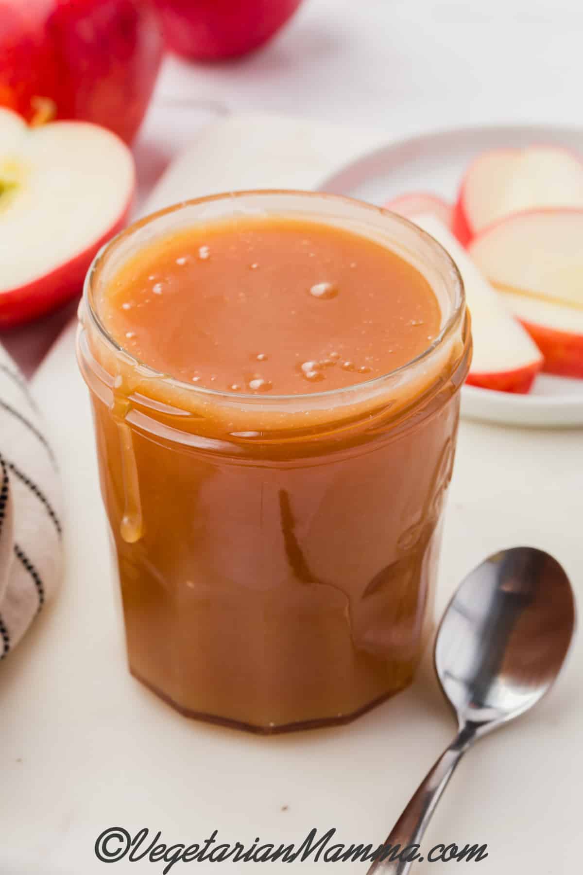 A jar filled with yummy caramel sauce with a spoon at the ready. 