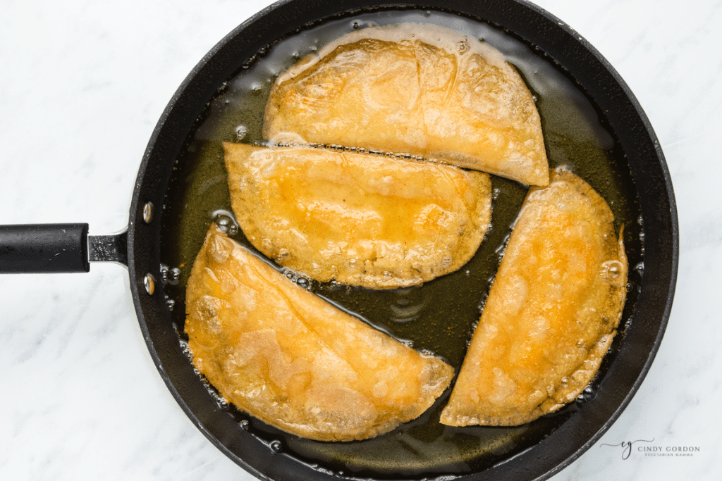 quesadillas frying in a pan with oil.