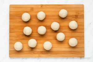 balls of tortilla dough on a wooden cutting board.