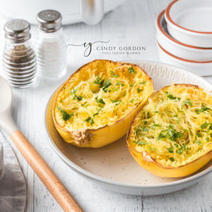 two halves of a spaghetti squash on a plate next to salt and pepper shakers.