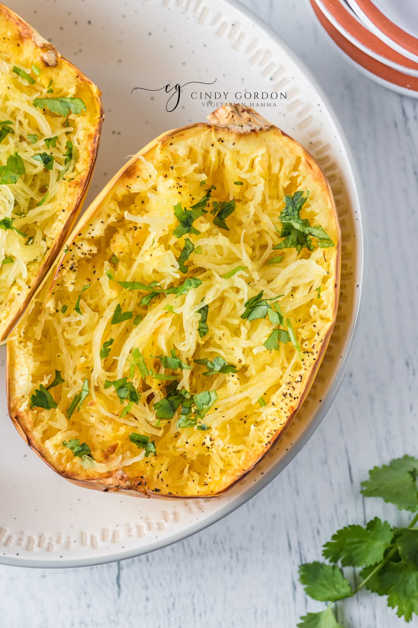 Air Fryer roasted spaghetti squash halves on a plate, topped with fresh herbs