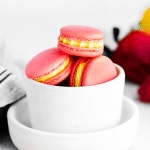 red and yellow strawberry lemon macarons in a bowl.