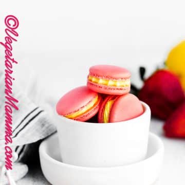 a bowl of dark pink strawberry macarons with lemon filling.