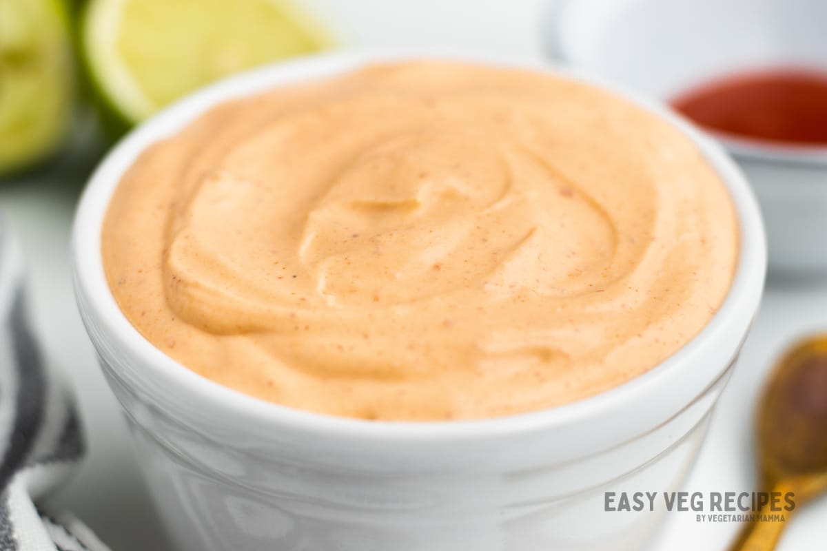 A white bowl filled to the brim with light orange chile crema dip. 
