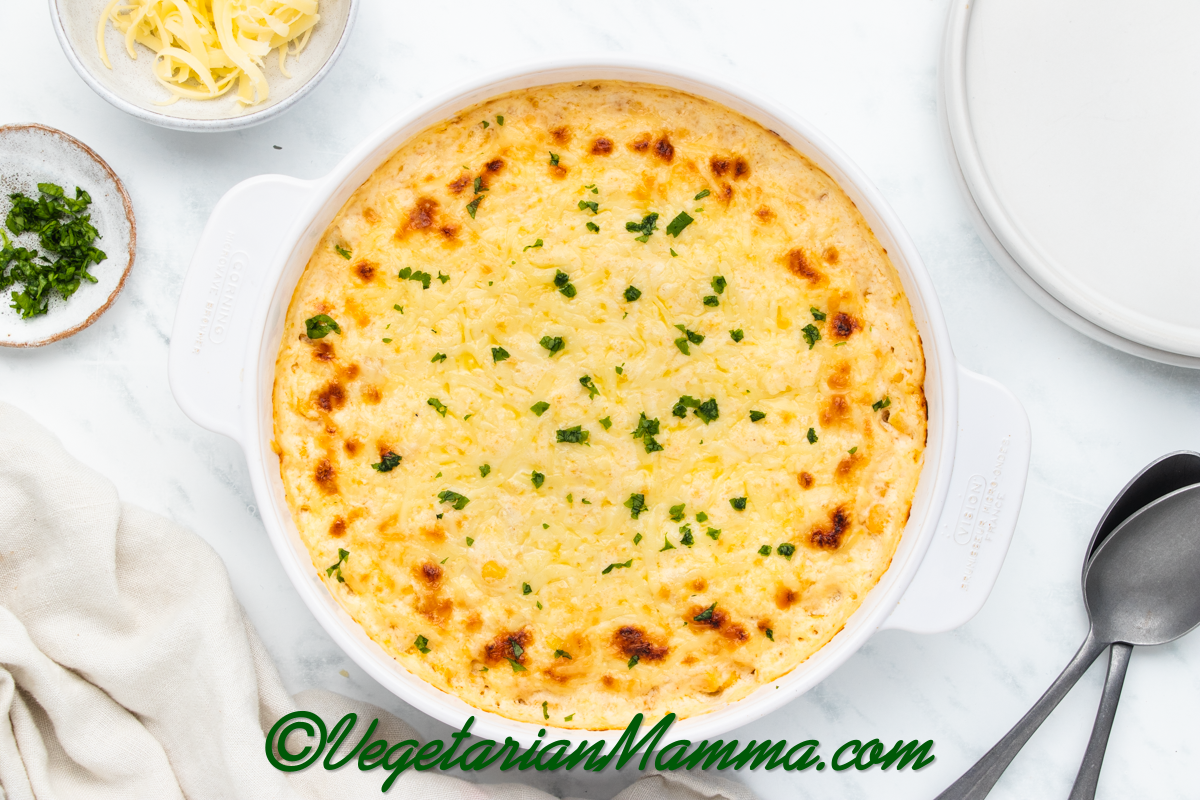 baked corn casserole with cream cheese in a round white dish.