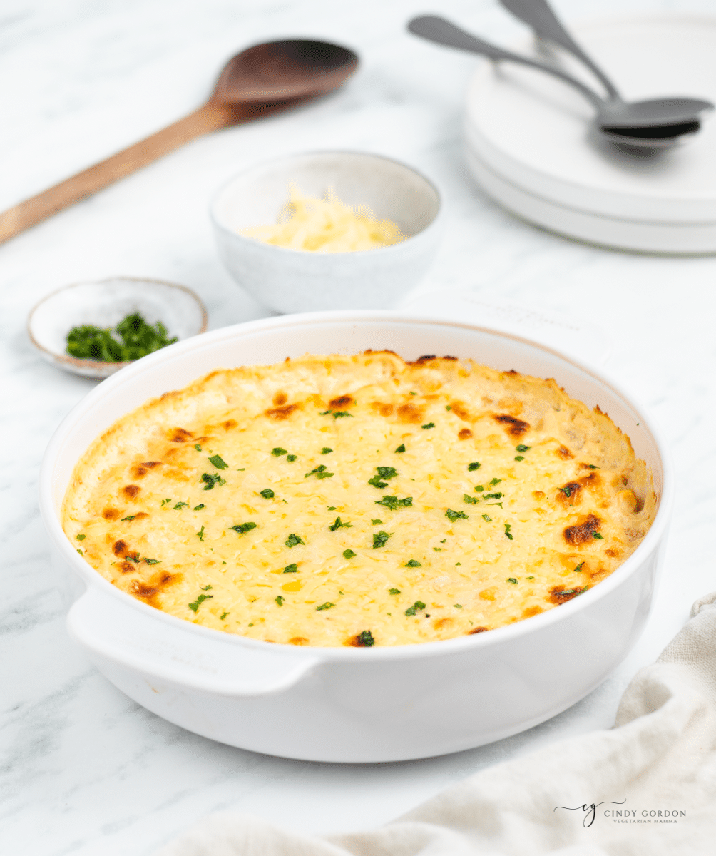 baked corn casserole with cream cheese in a round white dish.
