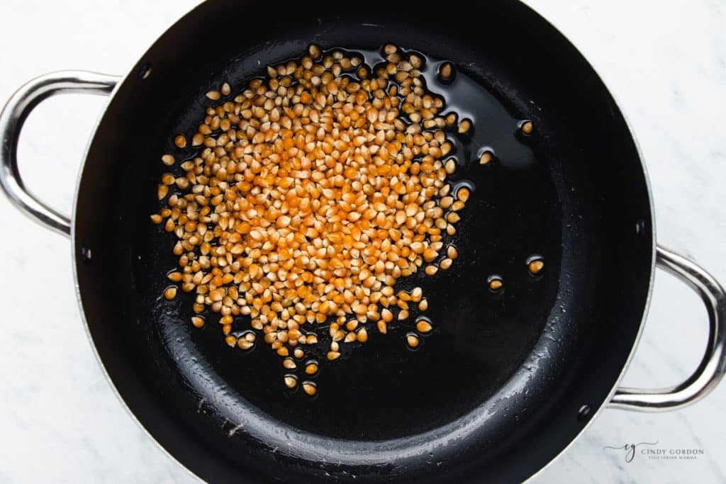 a large pot with oil and unpopped popcorn kernels in it.