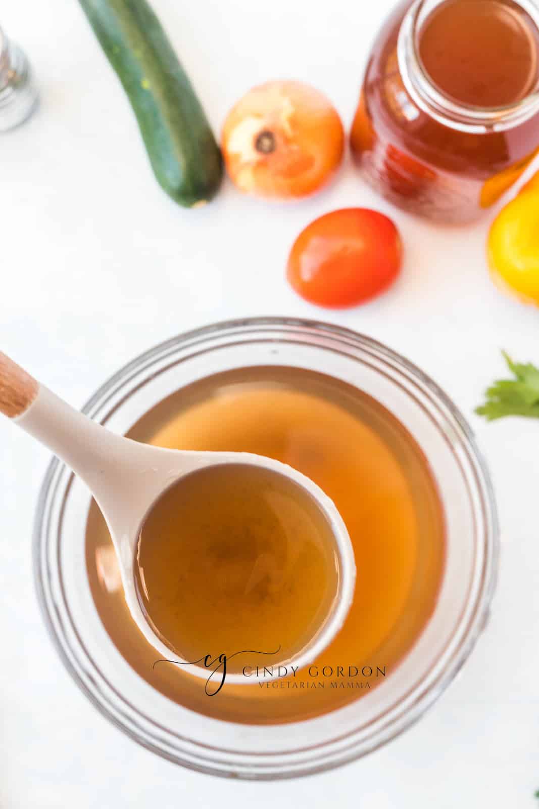 a ladle dipping into a jar of vegan chicken broth.