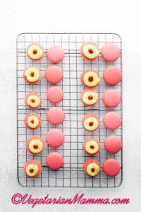 Place the macarons into similar sized pairs and pipe a ring of the lemon buttercream around the edge of one shell of each pair. Fill the center with strawberry jam and place the second macaron shell on top, pressing them together gently. Repeat with the remaining macarons.