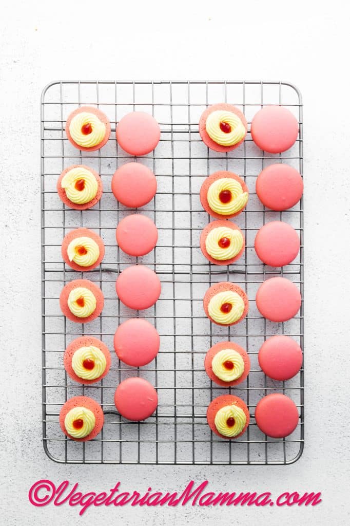 Place the macarons into similar sized pairs and pipe a ring of the lemon buttercream around the edge of one shell of each pair. Fill the center with strawberry jam and place the second macaron shell on top, pressing them together gently. Repeat with the remaining macarons.