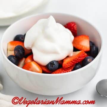 A bowl of berries topped with aquafaba whipped topping.