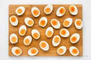 hard boiled eggs, peeled and cut in half, arranged on a cutting board.