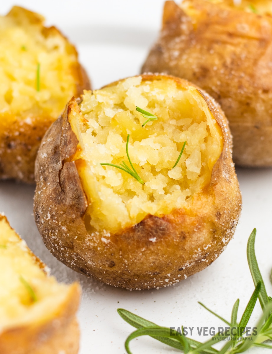 baked potatoes coated in salt, split open and sprinkled with rosemary.