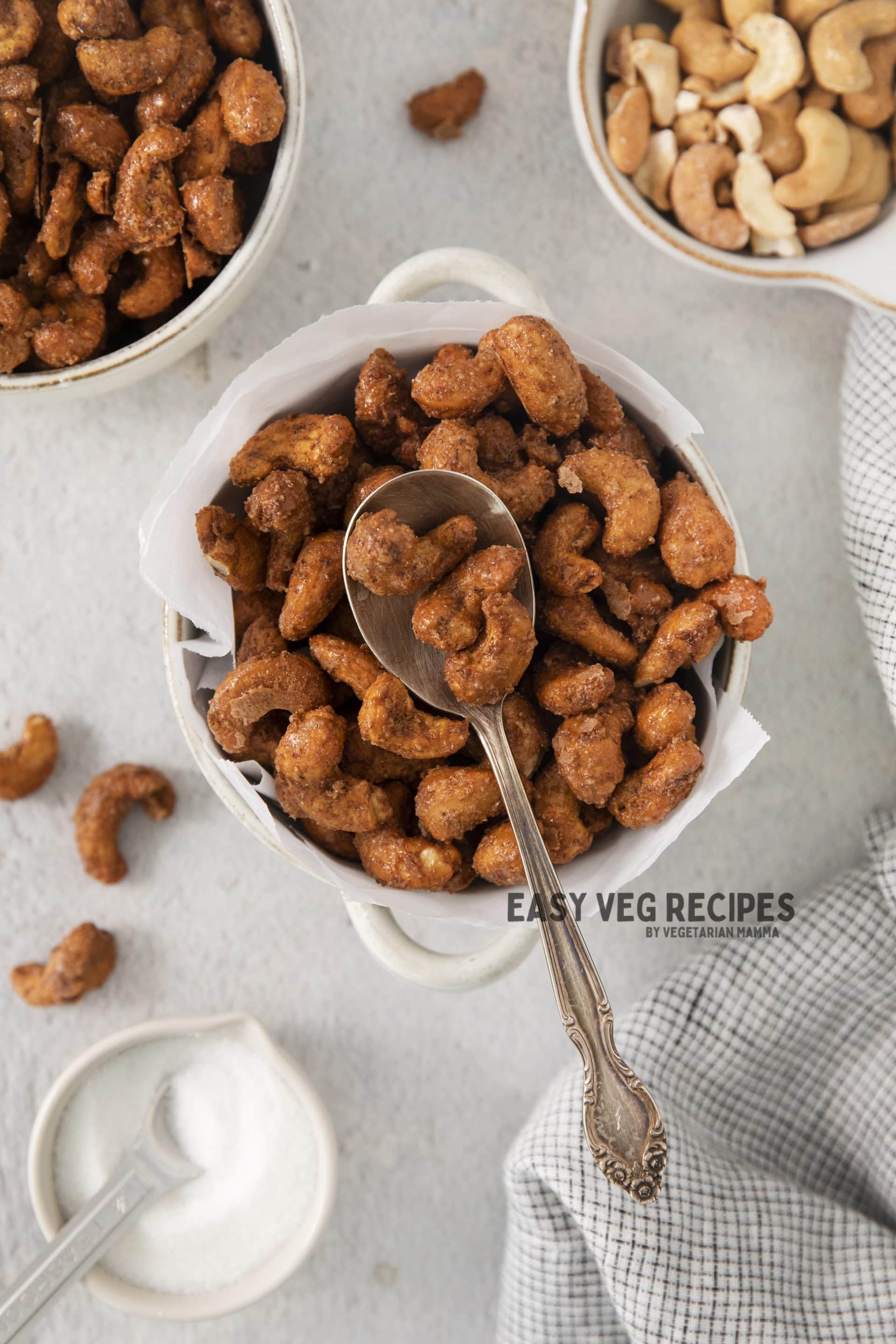 a bowl of candied cashews with a spoon it in. viewed from overhead