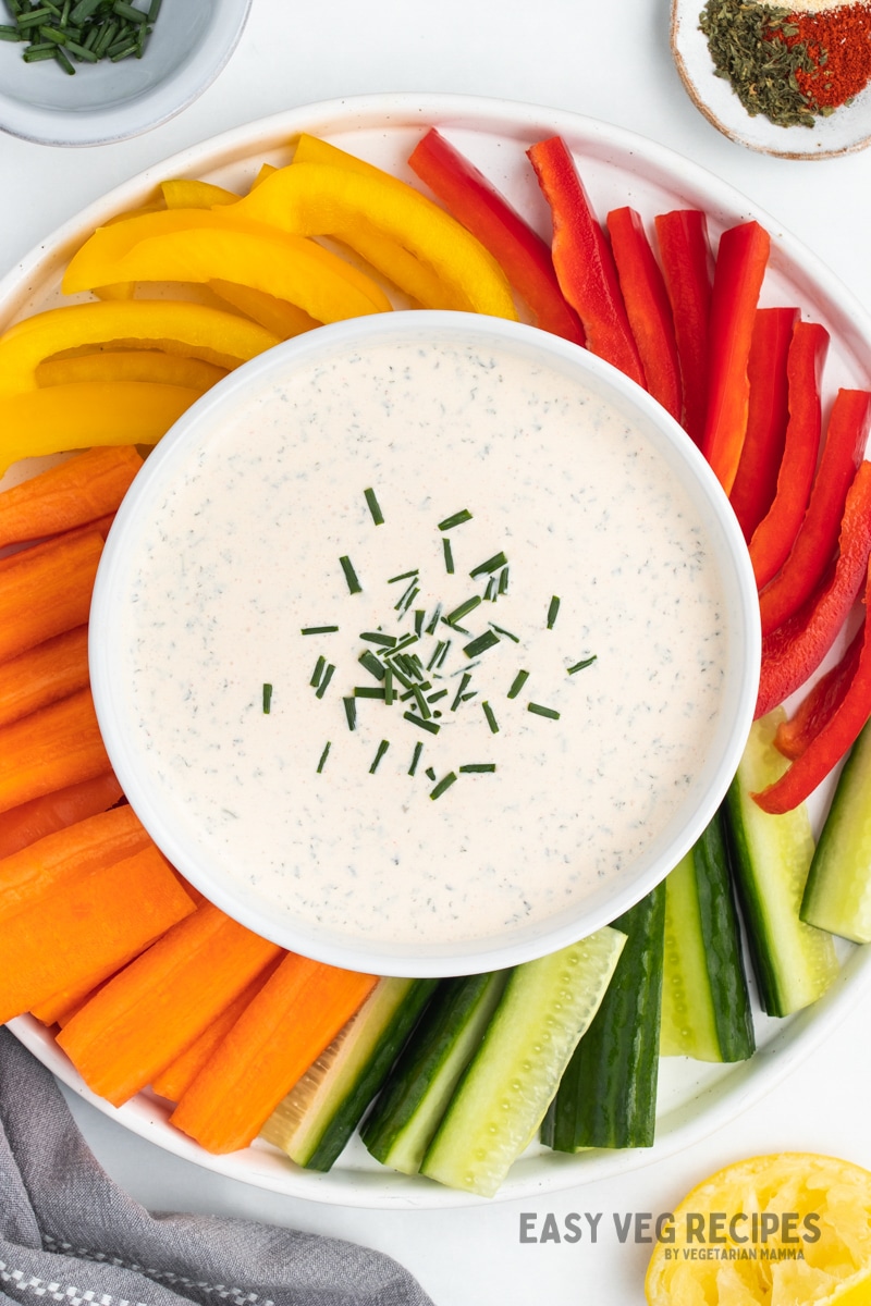 a bowl of seasoned sour cream dip surrounded by colorful vegetables. 
