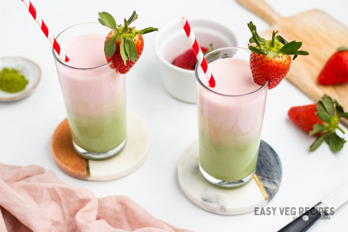 Finished matcha lattes in glasses with strawberry garnish and straws