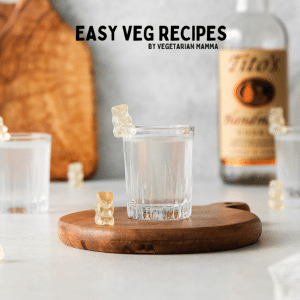 a small wooden tray holding a vodka shot with white gummy bears