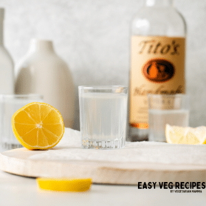 a white tea shot glass next to a lemon half.