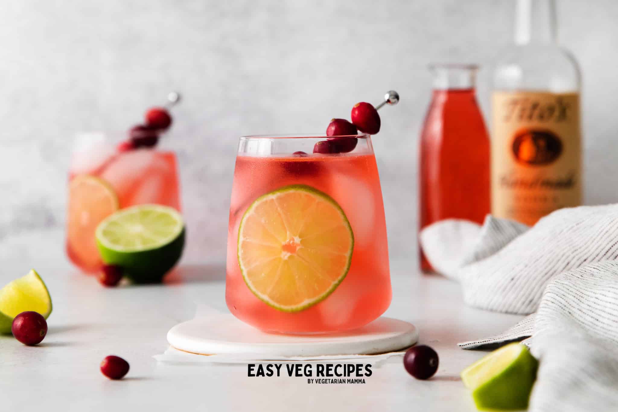 cosmos on rocks in a wide glass with a lime wheel and a cranberry skewer.