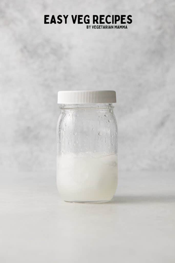 a glass jar with a plastic lid, used as a shaker for a white gummy bear shot