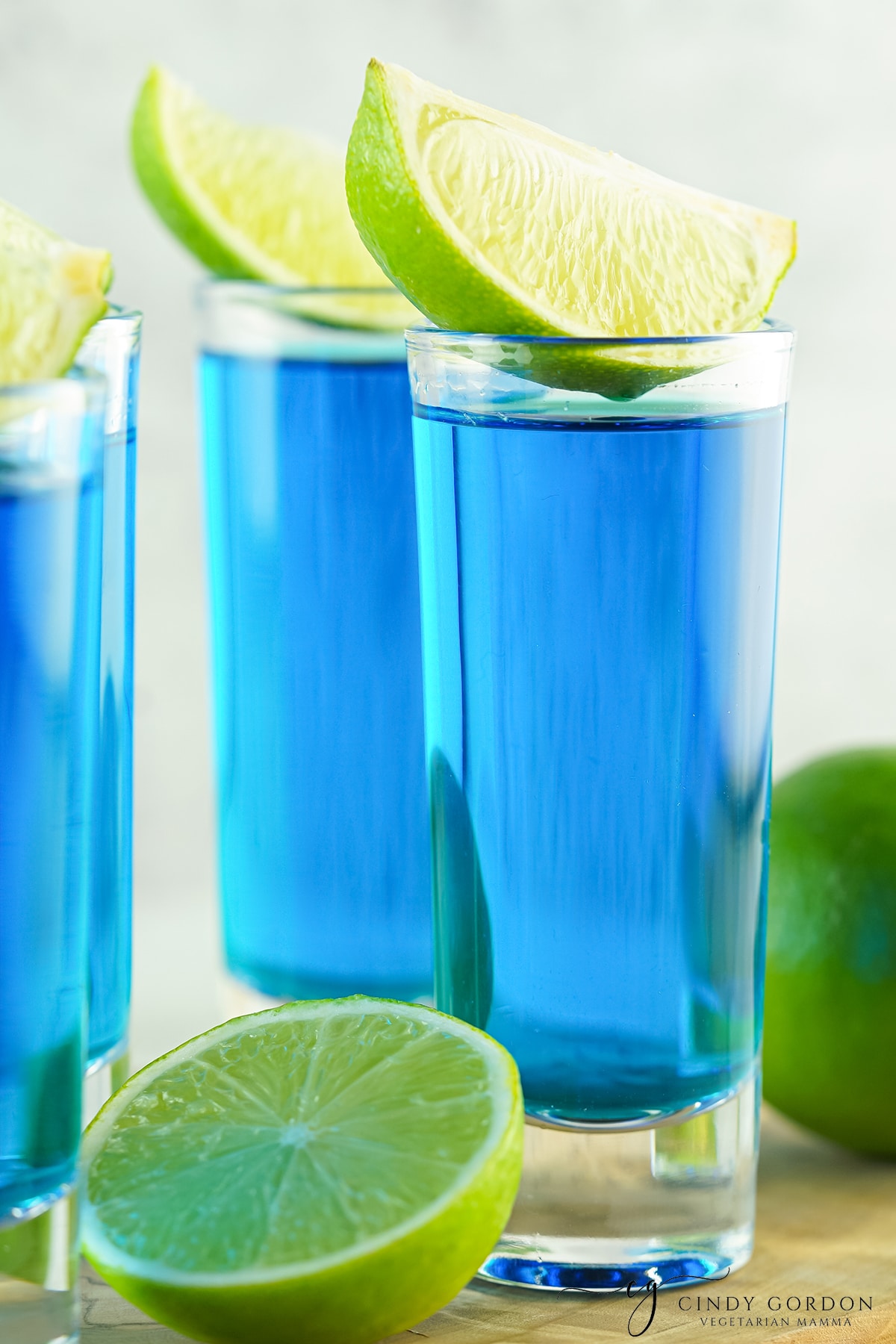 four tall blue shots topped with lime wedges.