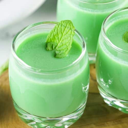small short glasses filled with dirty girl scout shot cocktails, garnished with mint leaves