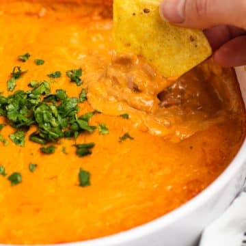 a chip scooping a taste of hot vegan buffalo chicken dip.