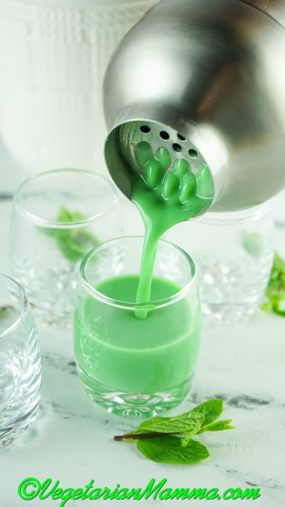 metal shaker pouring into a clear glass.