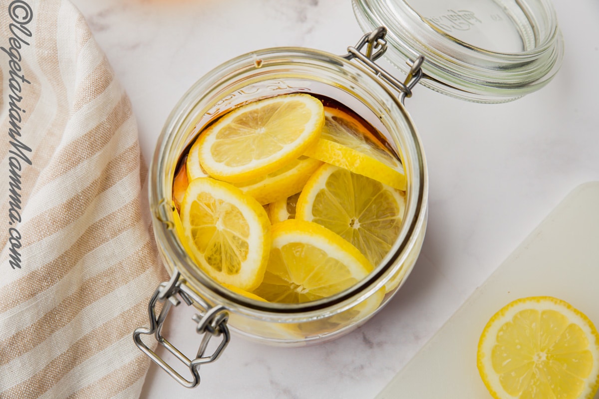 Jar filled with sliced lemons and a touch of honey