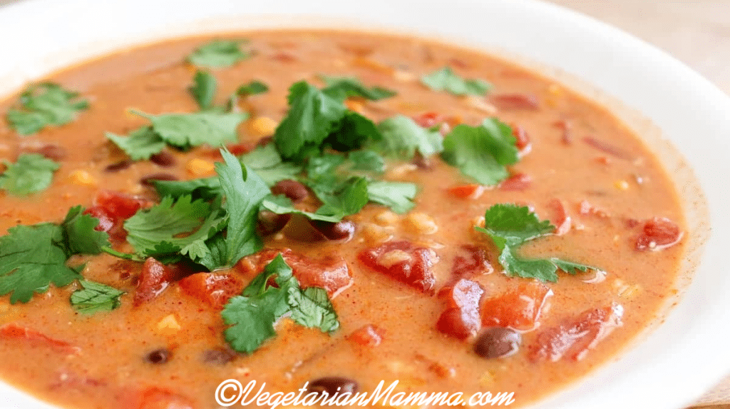 bowl of soup with cilantro and tomatoes.