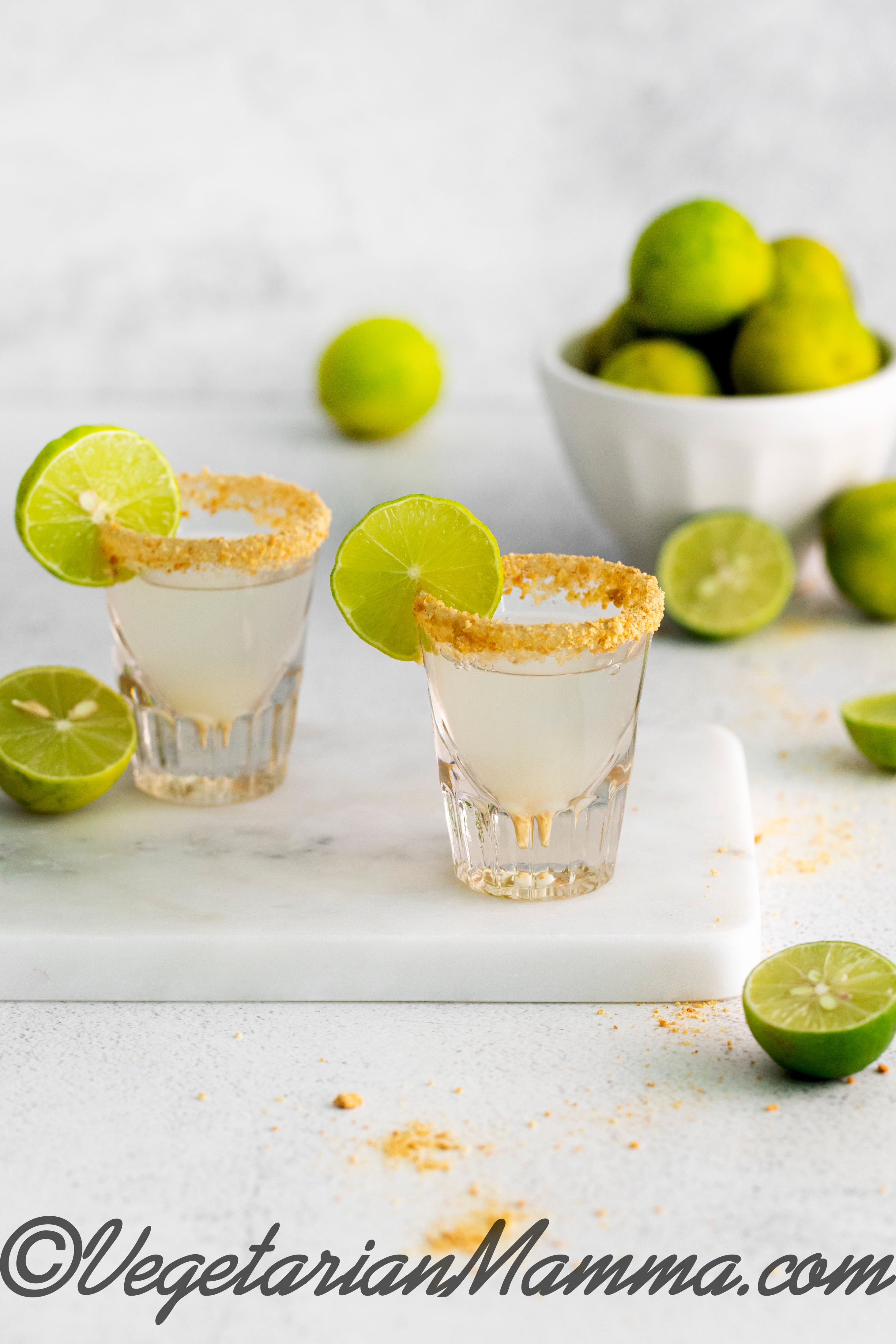 key lime pie shot with glass rimmed with graham cracker and a lime swirl.