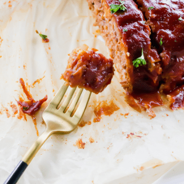 sliced meatloaf on parchment paper, made from beyond meat. a fork is holding a bite.
