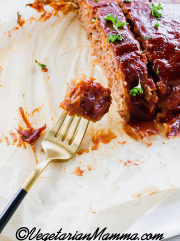 sliced meatloaf on parchment paper, made from beyond meat. a fork is holding a bite.