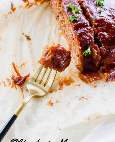 sliced meatloaf on parchment paper, made from beyond meat. a fork is holding a bite.