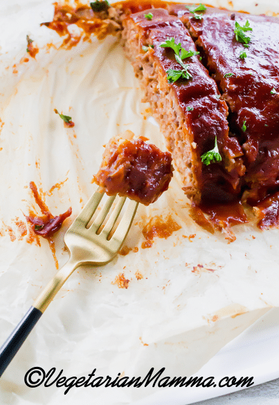 sliced meatloaf on parchment paper, made from beyond meat. a fork is holding a bite.