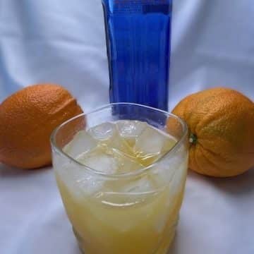 A glass of ice with OO7, two oranges, a bottle of blood orange sky vodka